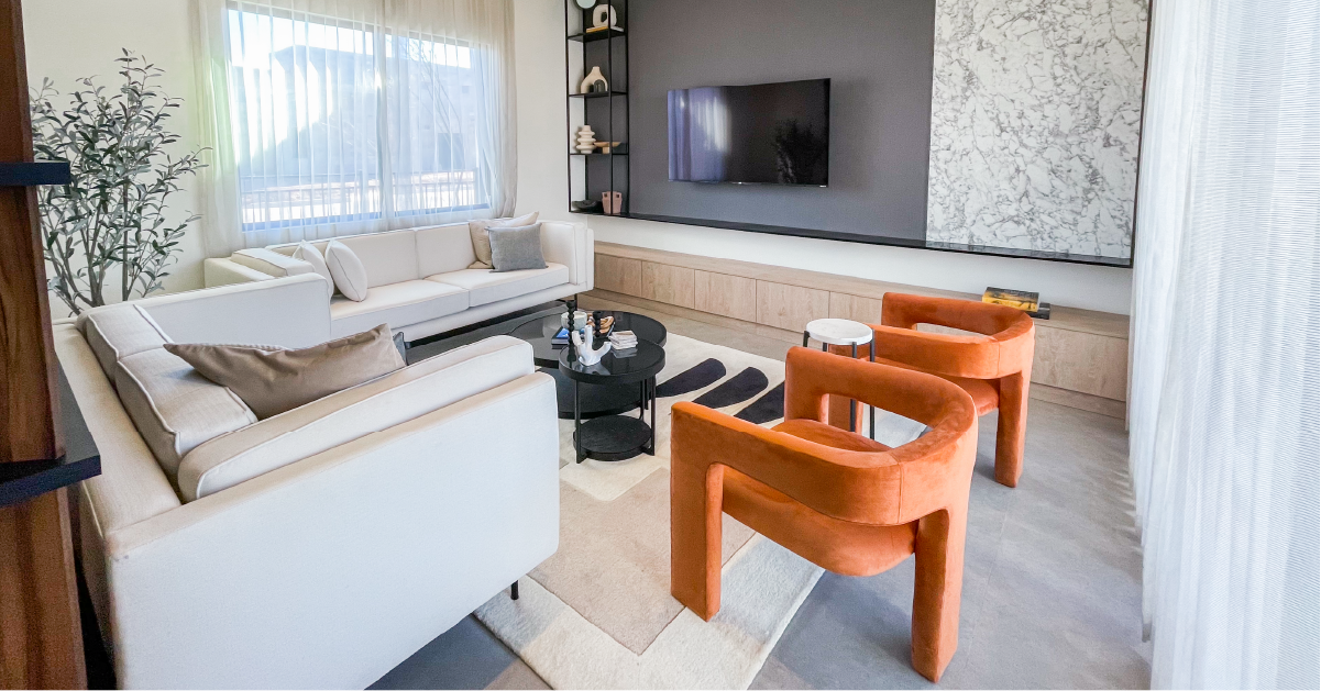Una sala de estar contemporánea que exhibe elegantes muebles blancos complementados con vibrantes sillas de color naranja
