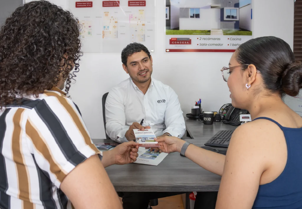 Pareja siendo guiada por asesor de Exe inmobiliaria sobre un crédito hipotecario de interés