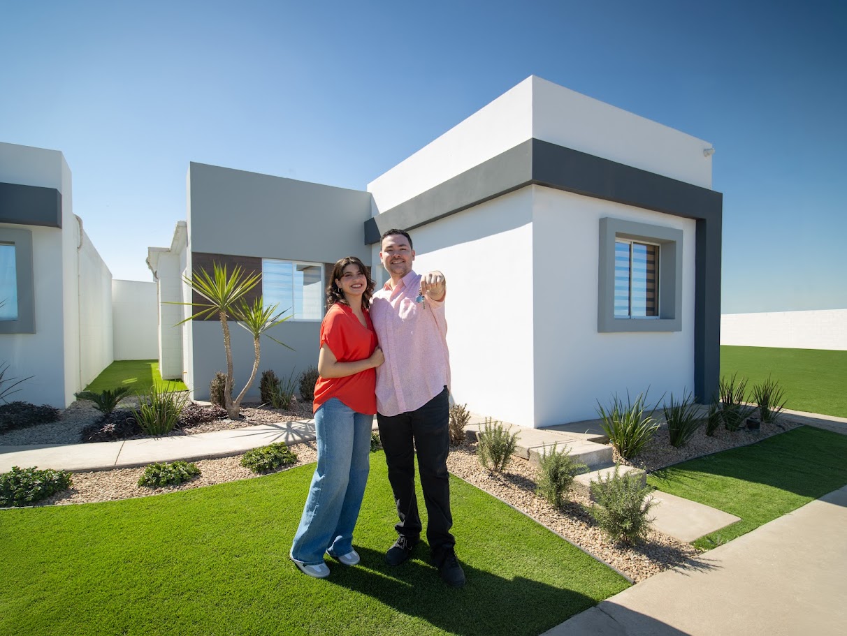 Pareja sentada alegremente en la sala de su casa nueva de una planta